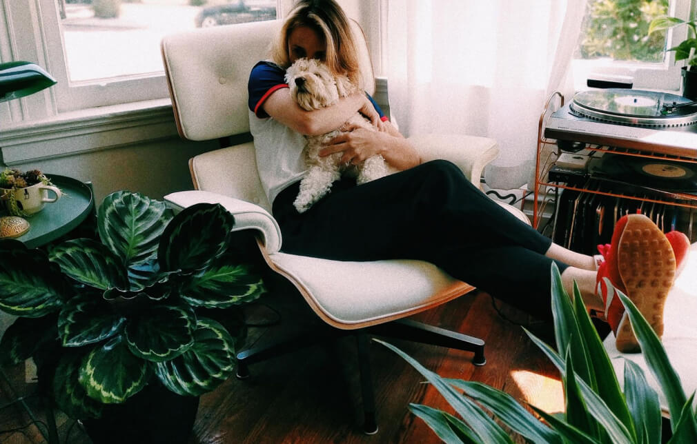 En kvinna som sitter i en fåtölj med en hund i knät
