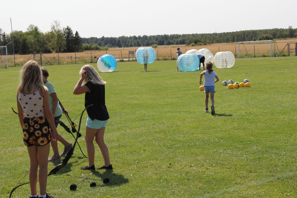 Barn som leker och kör bumperball på gräsyta