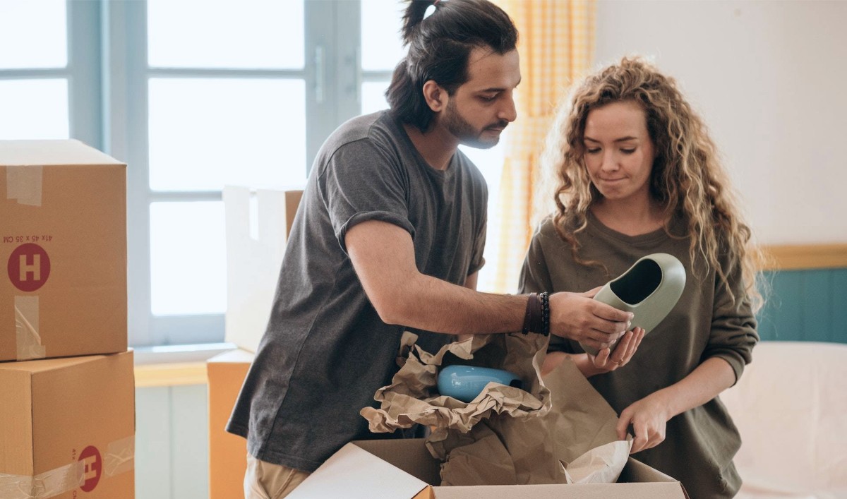 Kvinna och man håller på att packa flyttkartonger